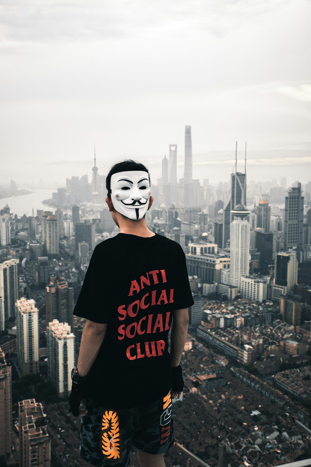 man standing on rooftop facing high rise buildings