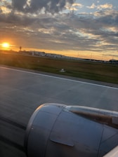 An aerial view of an airplane taking off next to a vibrant airport runway at sunrise.