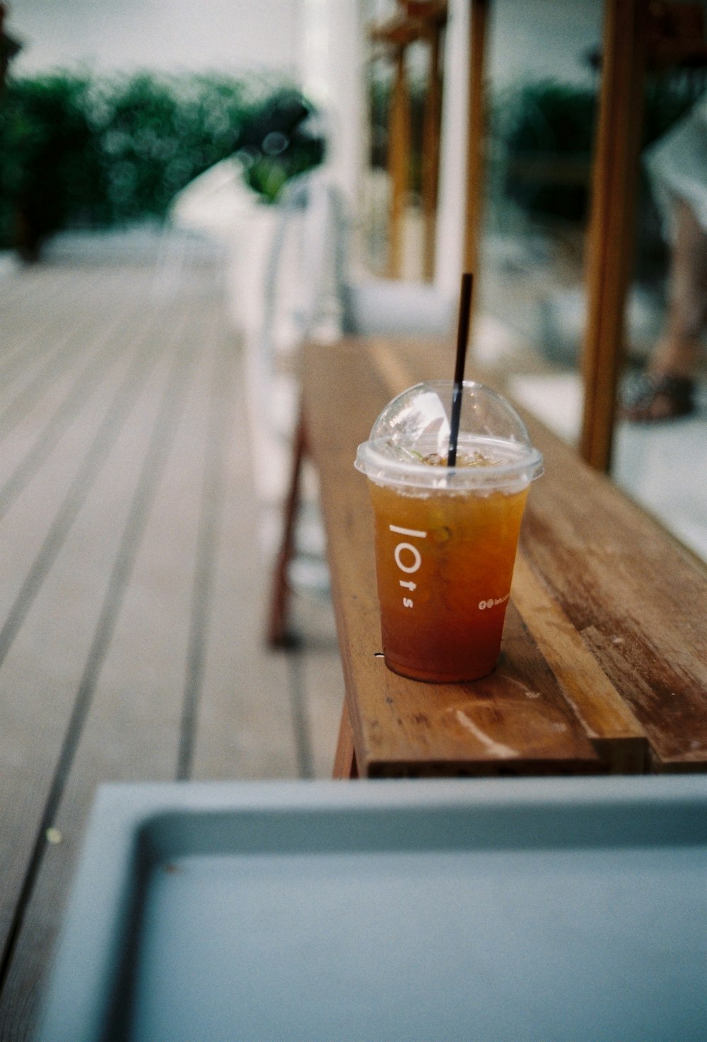 clear plastic cup with coffee on bench