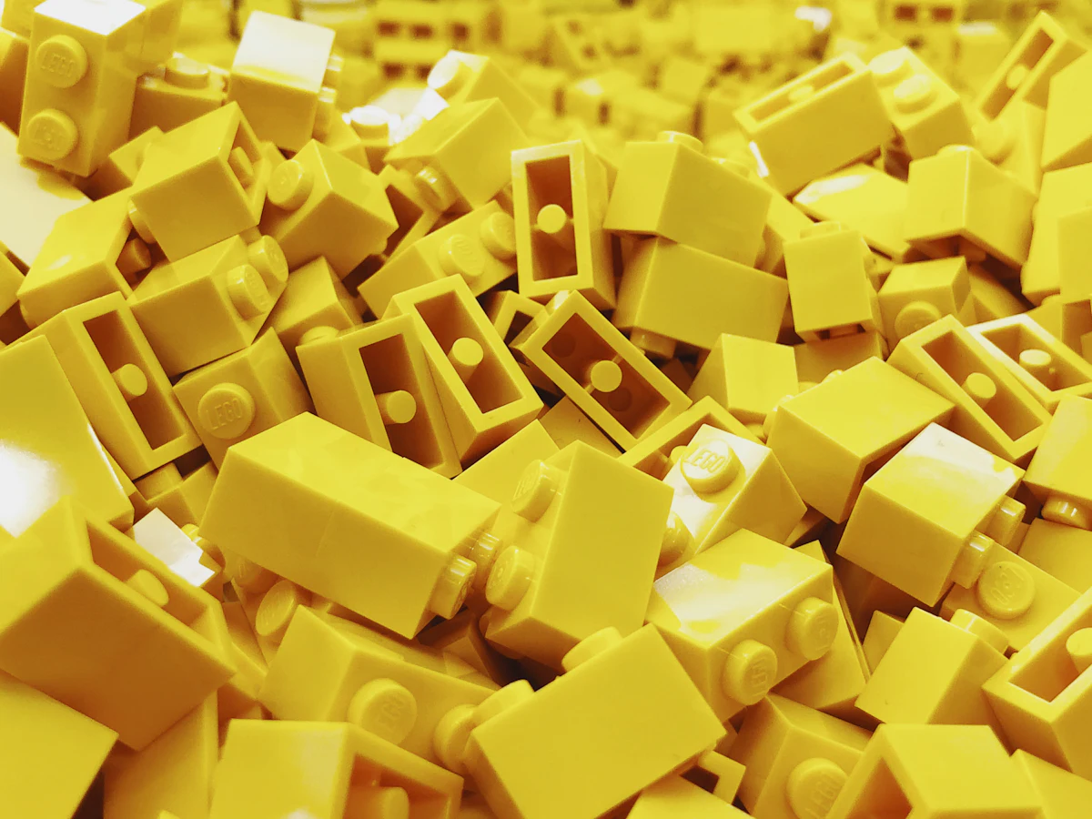 Tumpukan brick LEGO kuning sebagai analogi mata uang studs yang dikumpulkan saat bermain LEGO Batman Legacy of the Dark Knight