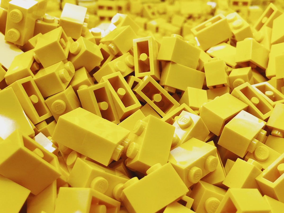 Tumpukan brick LEGO kuning sebagai analogi mata uang studs yang dikumpulkan saat bermain LEGO Batman Legacy of the Dark Knight