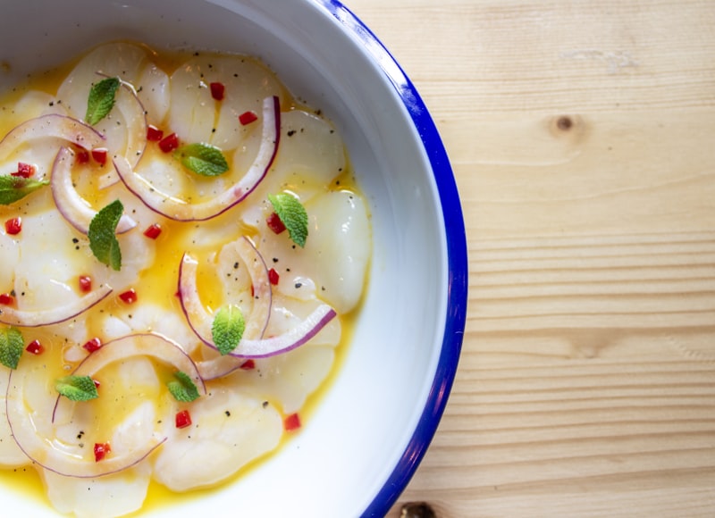 White fish in a golden butter sauce with sliced onions in a bowl