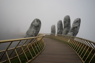 close-up photography of the railings of a bridge being held by a giant sculptured hand