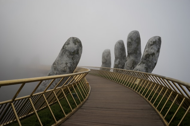 close-up photography of the railings of a bridge being held by a giant sculptured hand