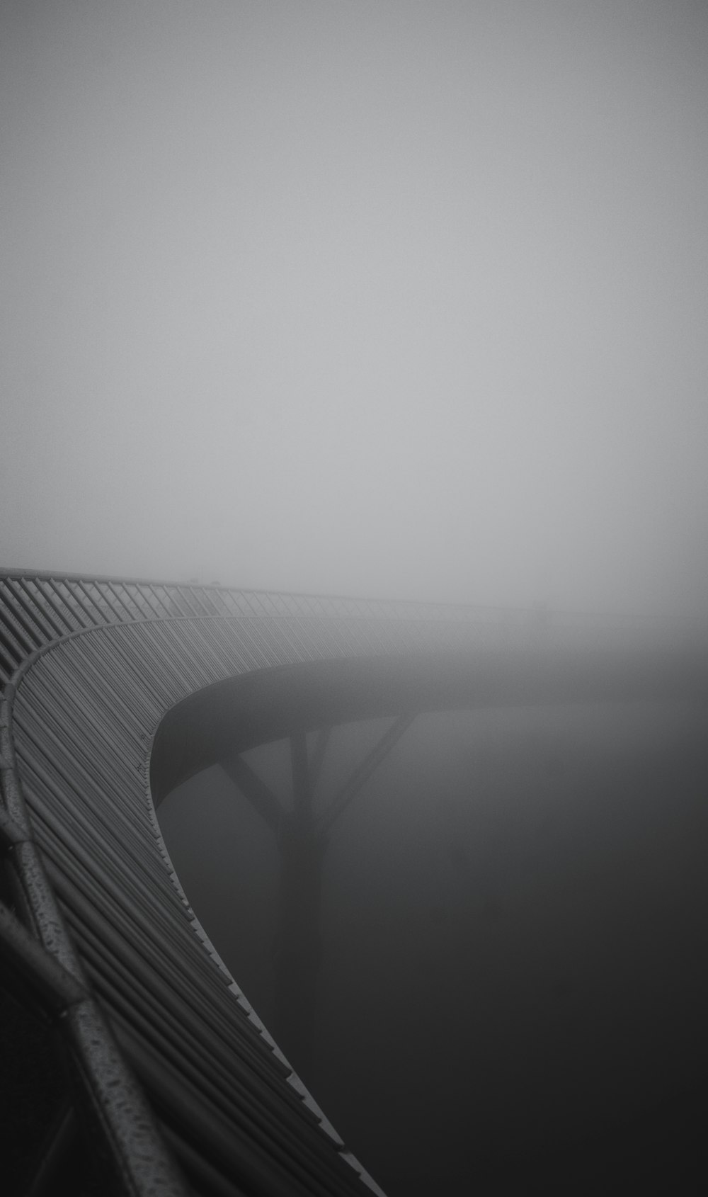 a black and white photo of a bridge in the fog