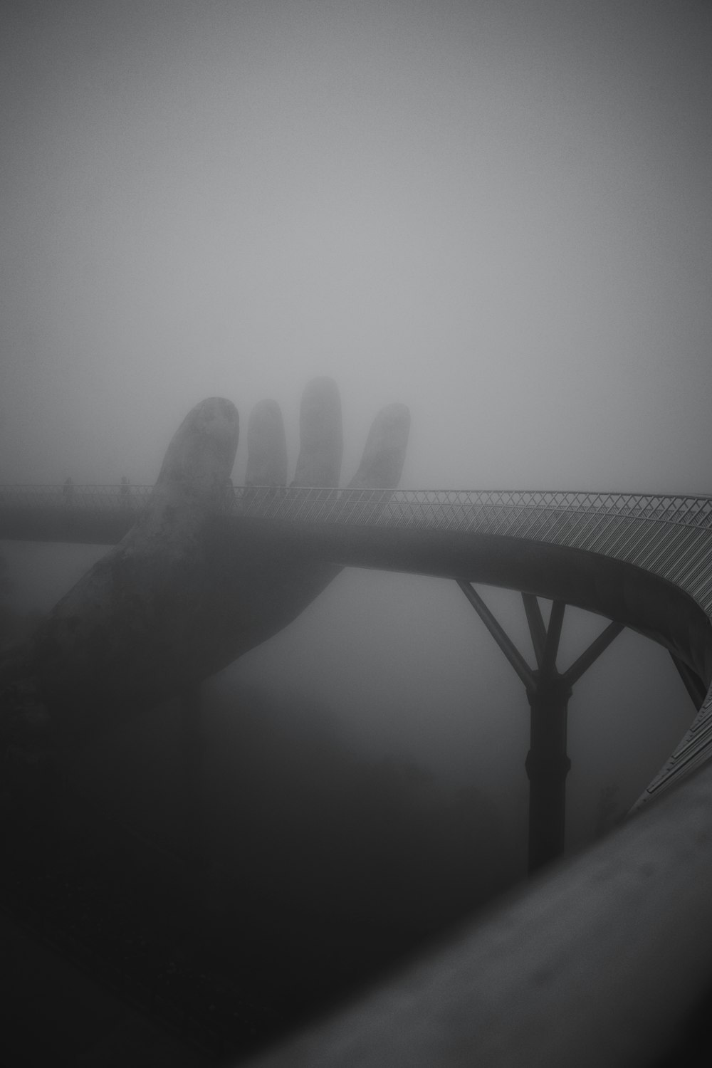 grayscale photography of hand holding bridge