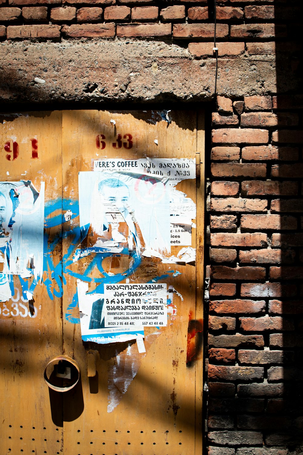 a wooden door with graffiti on it next to a brick wall