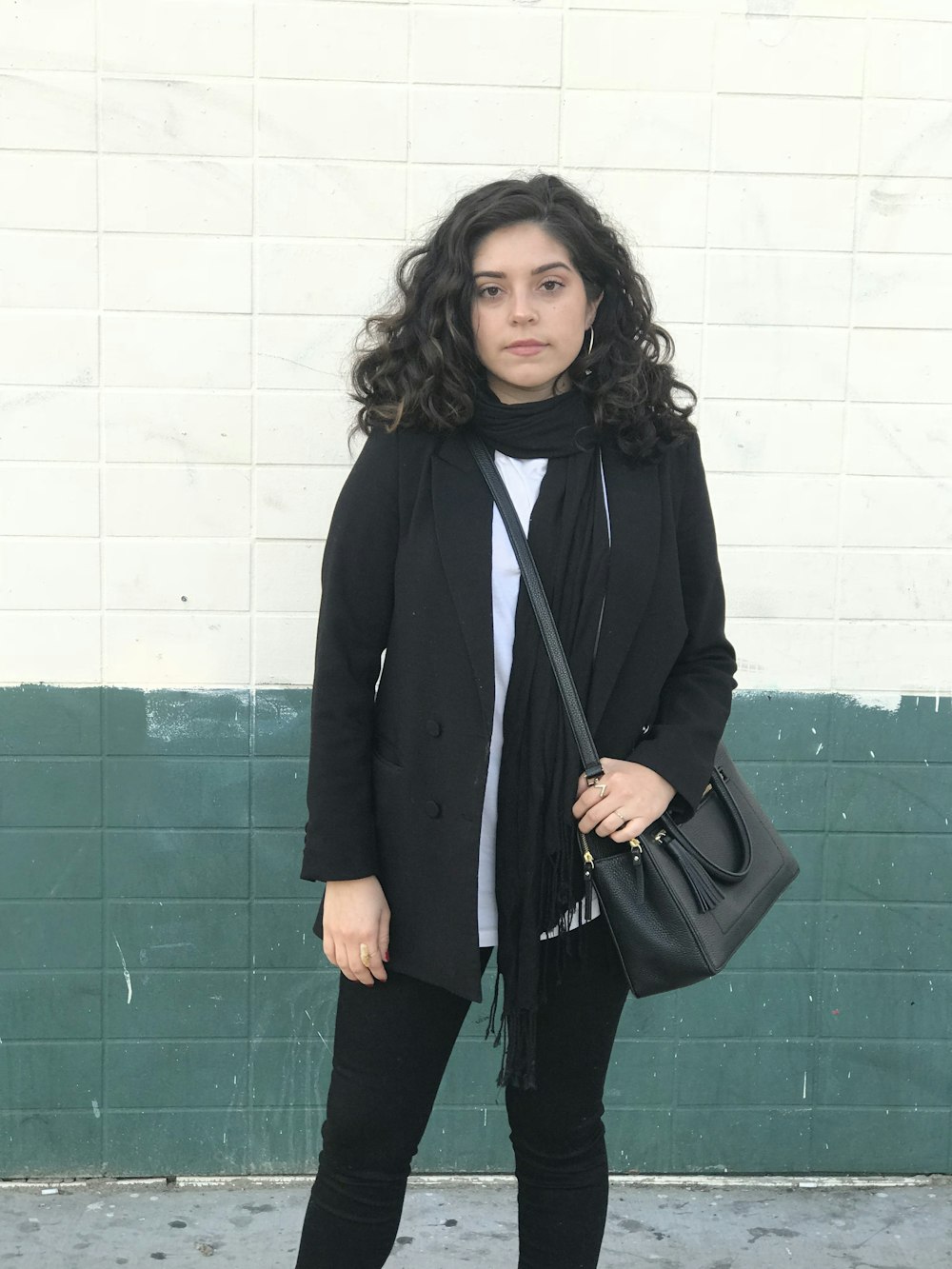 woman wearing bag and jacket standing near wall