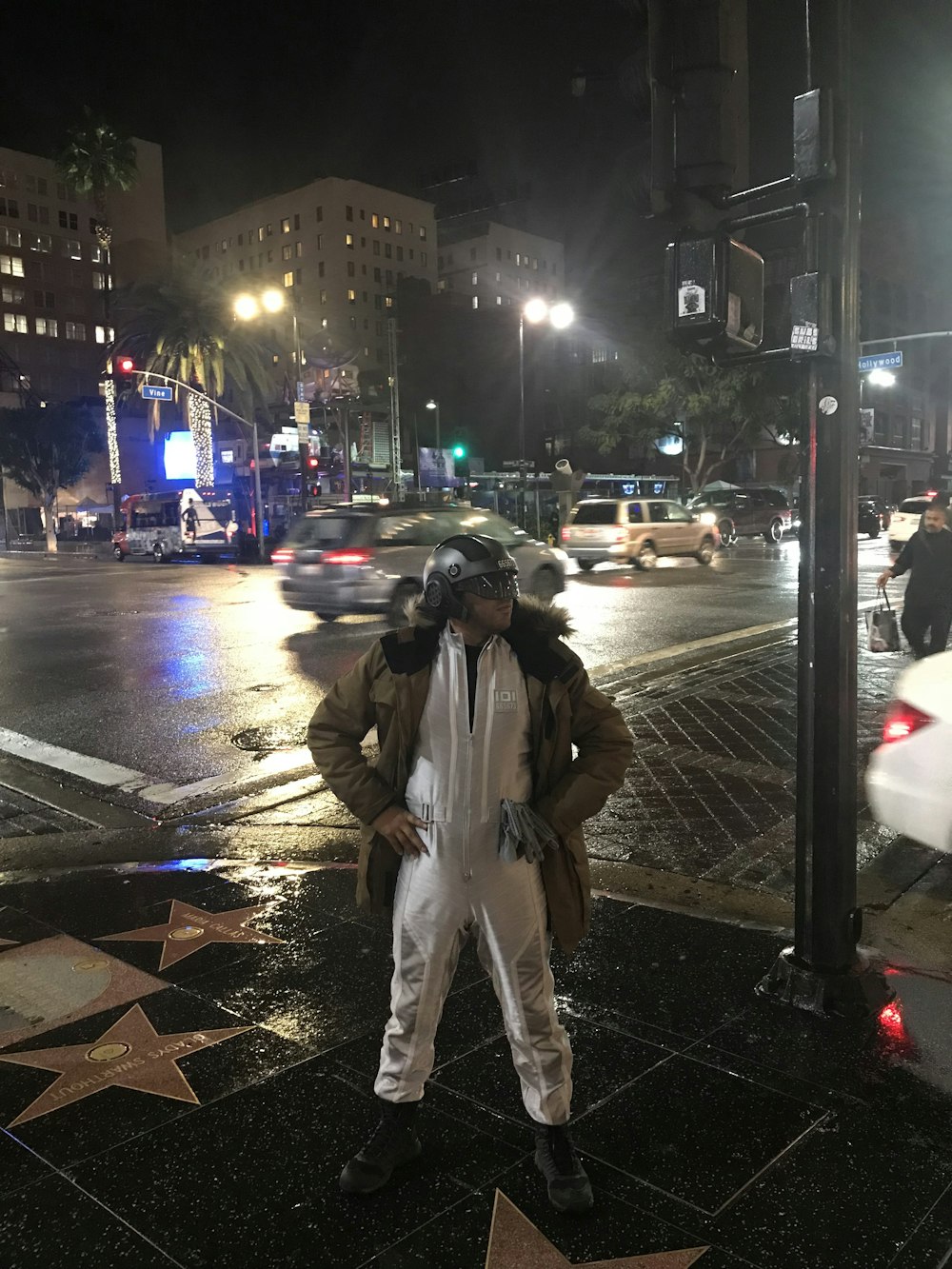 man in white jumpsuit with brown jacket posing near road