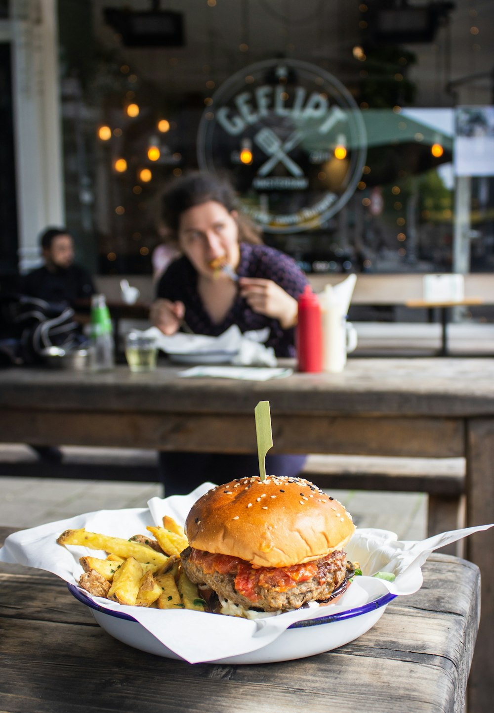 hamburger with fries in dish on table