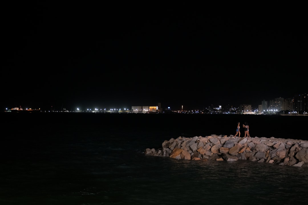 people on rocks beside water,