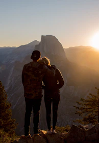 Close-up of hikers sharing a moment together on a mountain path at sunset.