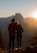 A couple standing on a scenic overlook, gazing at a breathtaking landscape during sunset.