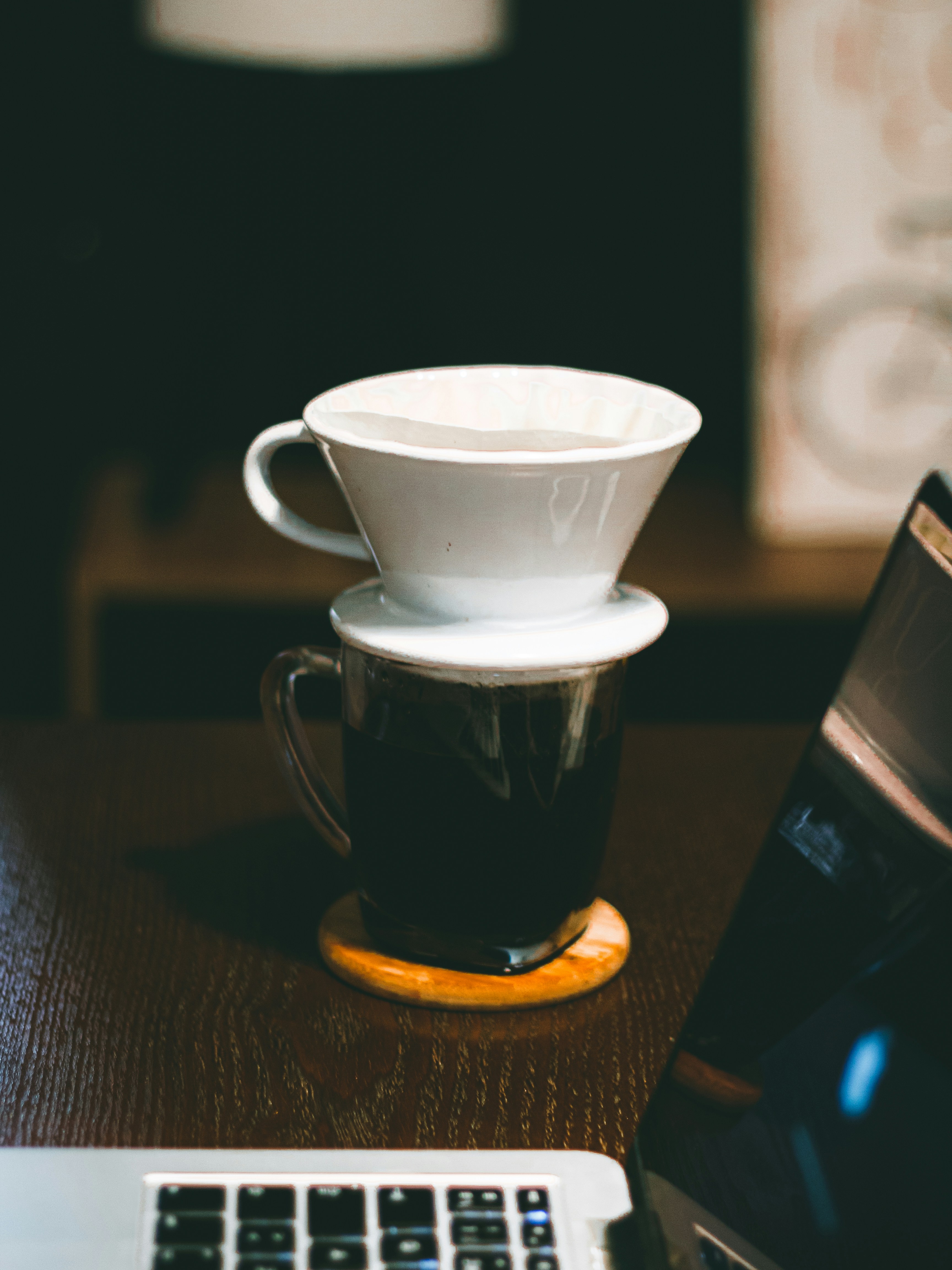 white ceramic cup on top of full black ceramic mug on table