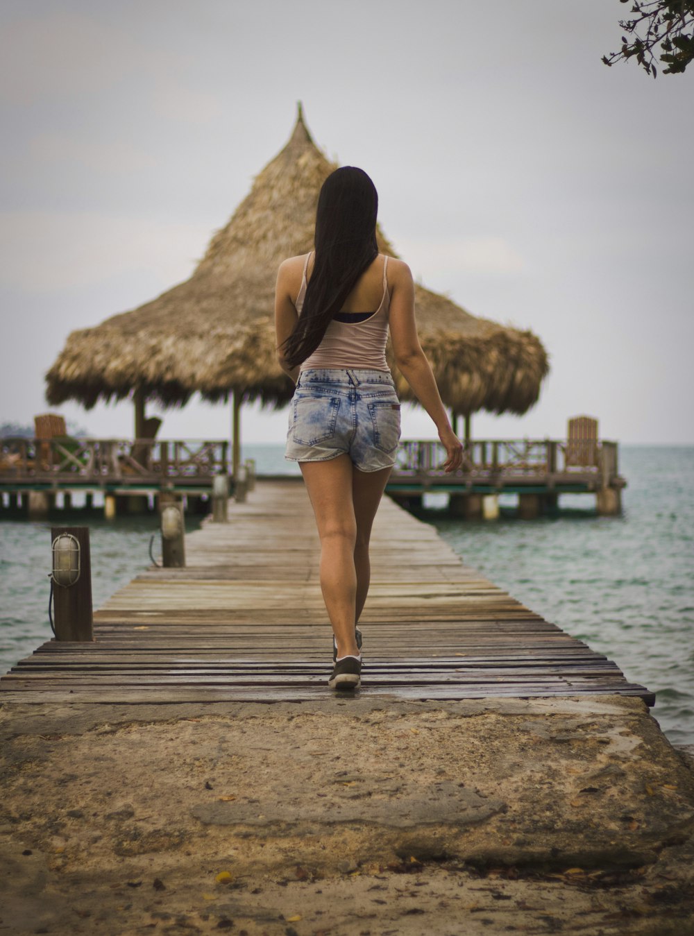 woman walking on gray wooden dock near sea