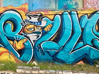 A dynamic street art mural featuring the $wif hat and the phrase 'the hat stays on' in bold colors.