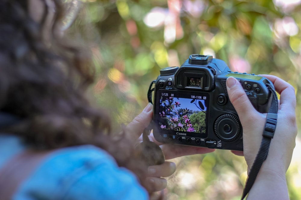 woman holding black DSLR camera