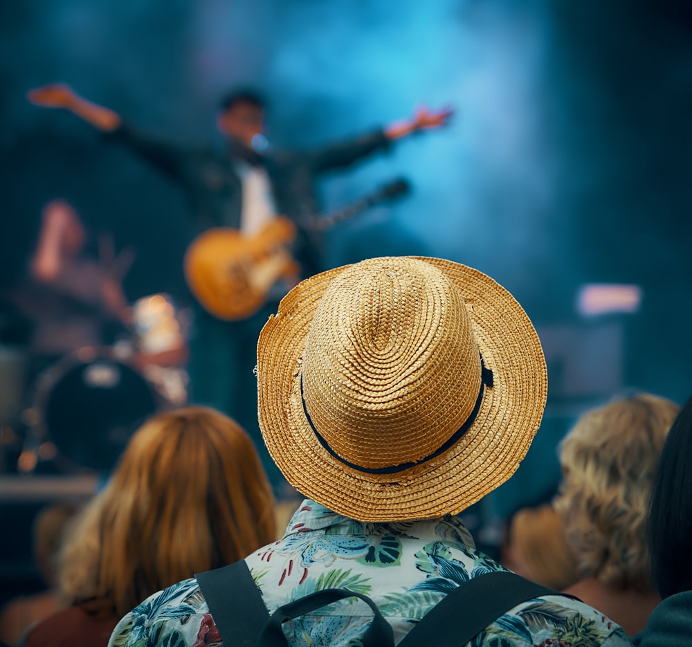 man with guitar standing on stage in front of crowd