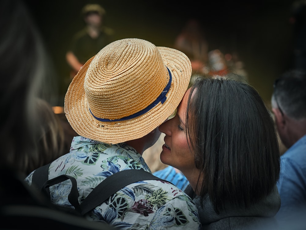 woman whispering on man's right ear with fedora hat
