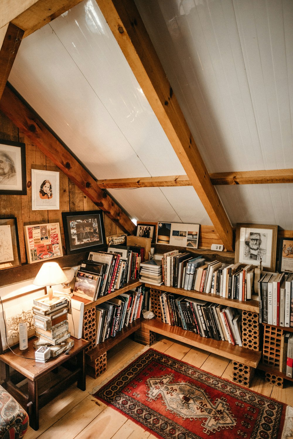 books in bookcase by turned-on table lamp