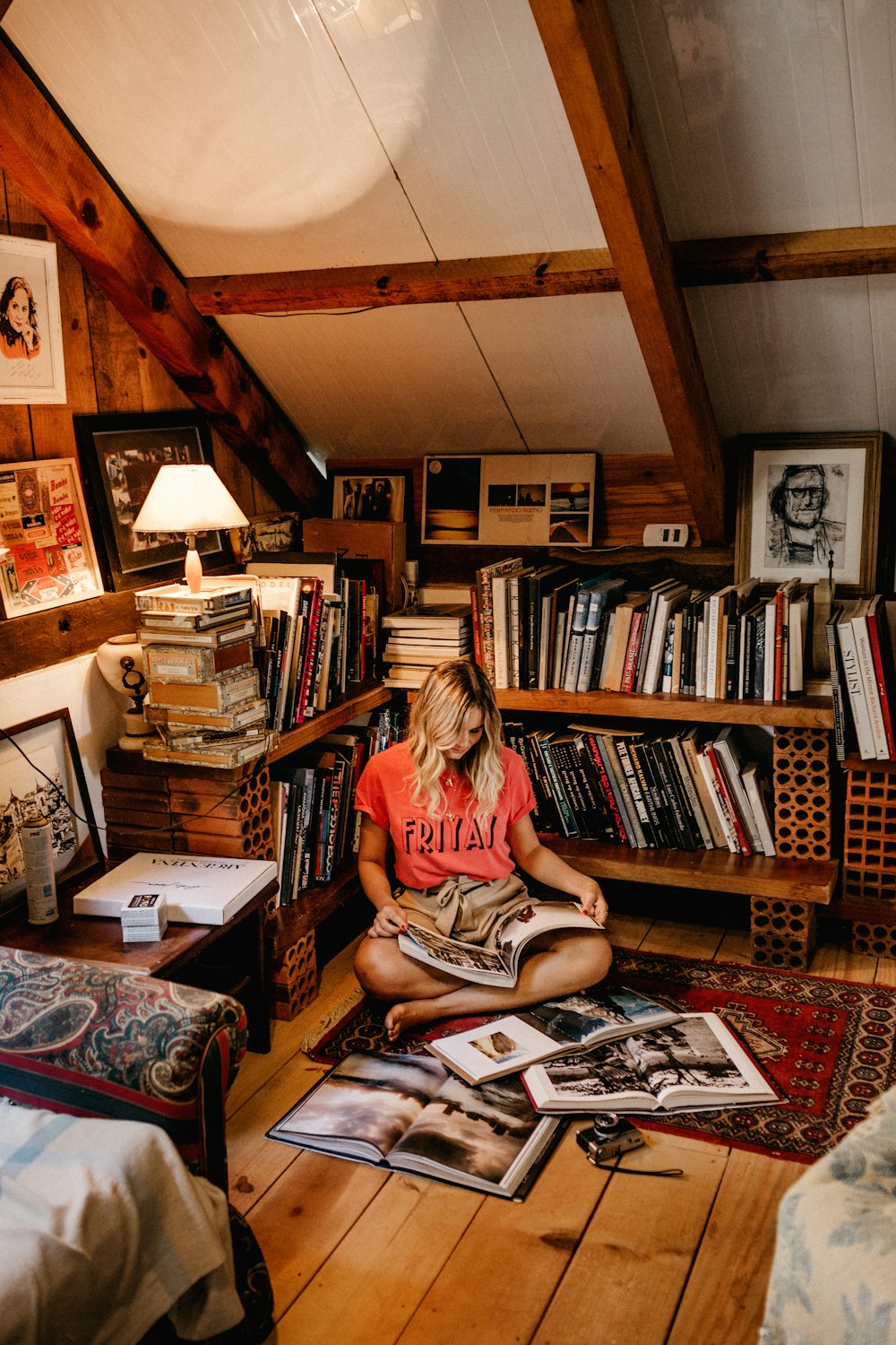 femme assise sur le sol lisant un livre devant une bibliothèque