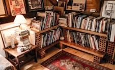 assorted books in shelf near lighted table lamp