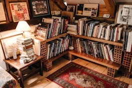 assorted books in shelf near lighted table lamp