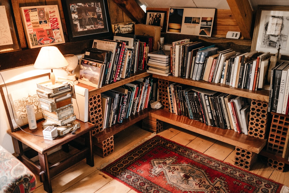 assorted books in shelf near lighted table lamp