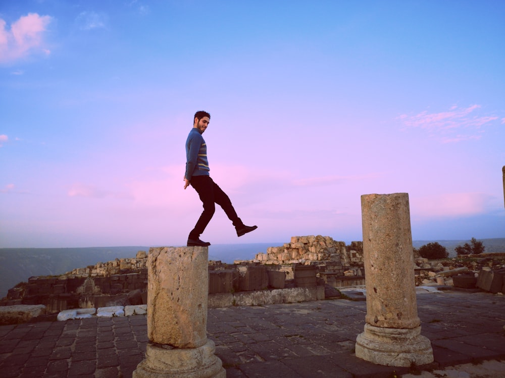 man in blue sweater standing on concrete pavement