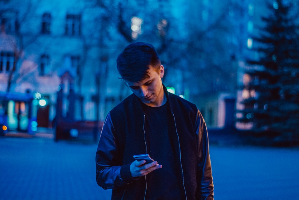 man standing and using phone on pathway