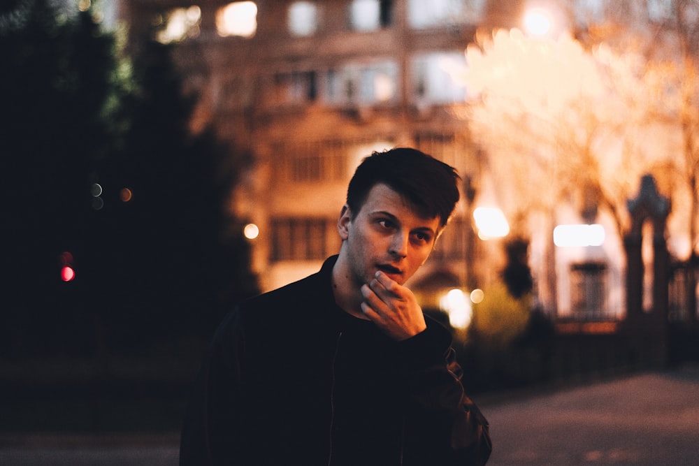 man touching his chin near building