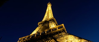 Close-up detail of the Burj Khalifa’s illuminated spire piercing the night sky against a black backdrop.