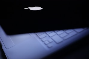 A close-up of a refurbished laptop with a glowing screen on a wooden desk.