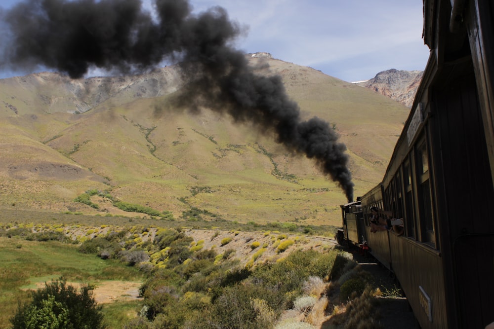 black train near green field and mountain