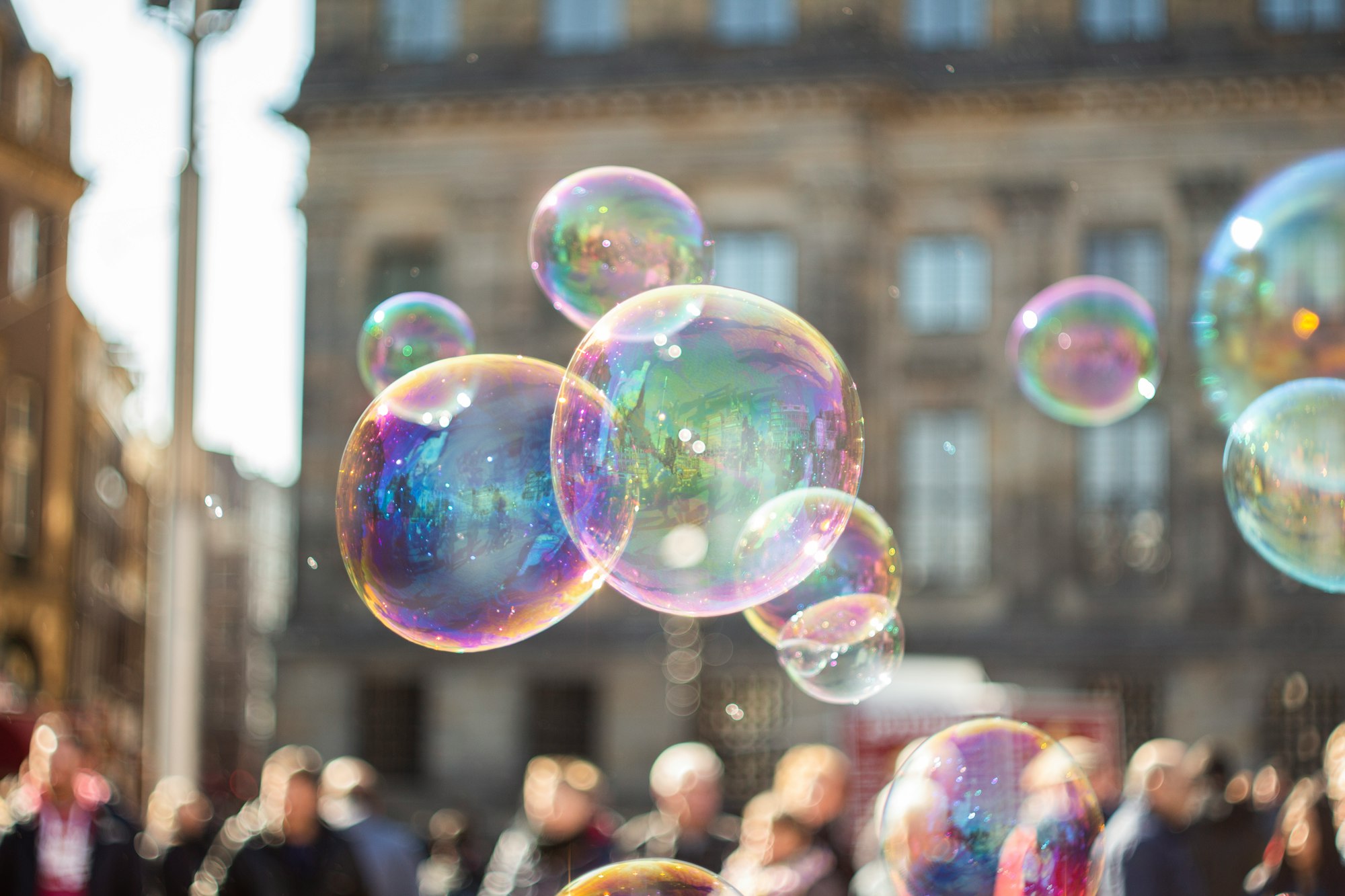 several iridescent soap bubbles with a blurry crowd in the distance