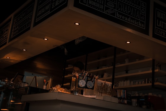 A cozy cafe interior with warm lighting, wooden tables, and a friendly barista preparing a fresh panini.
