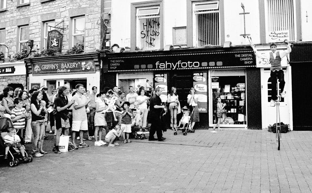 grayscale photo of people watching a unicyclist