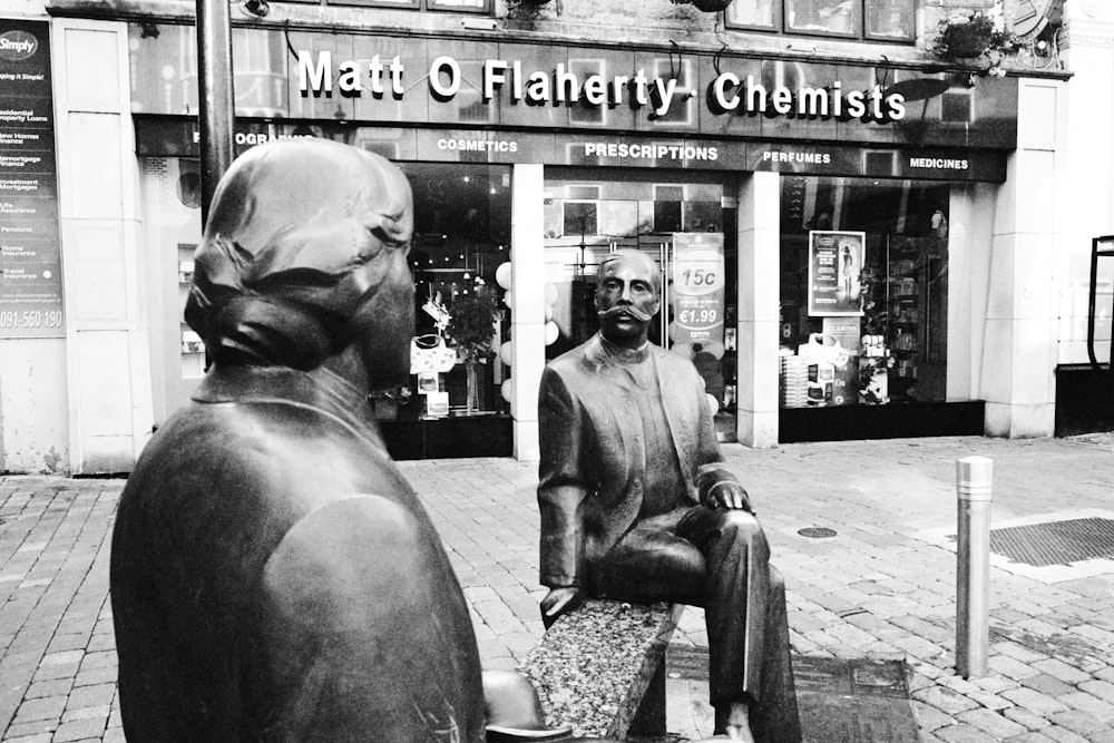 sitting man statue in front of Matt O Flaherty Chemists store
