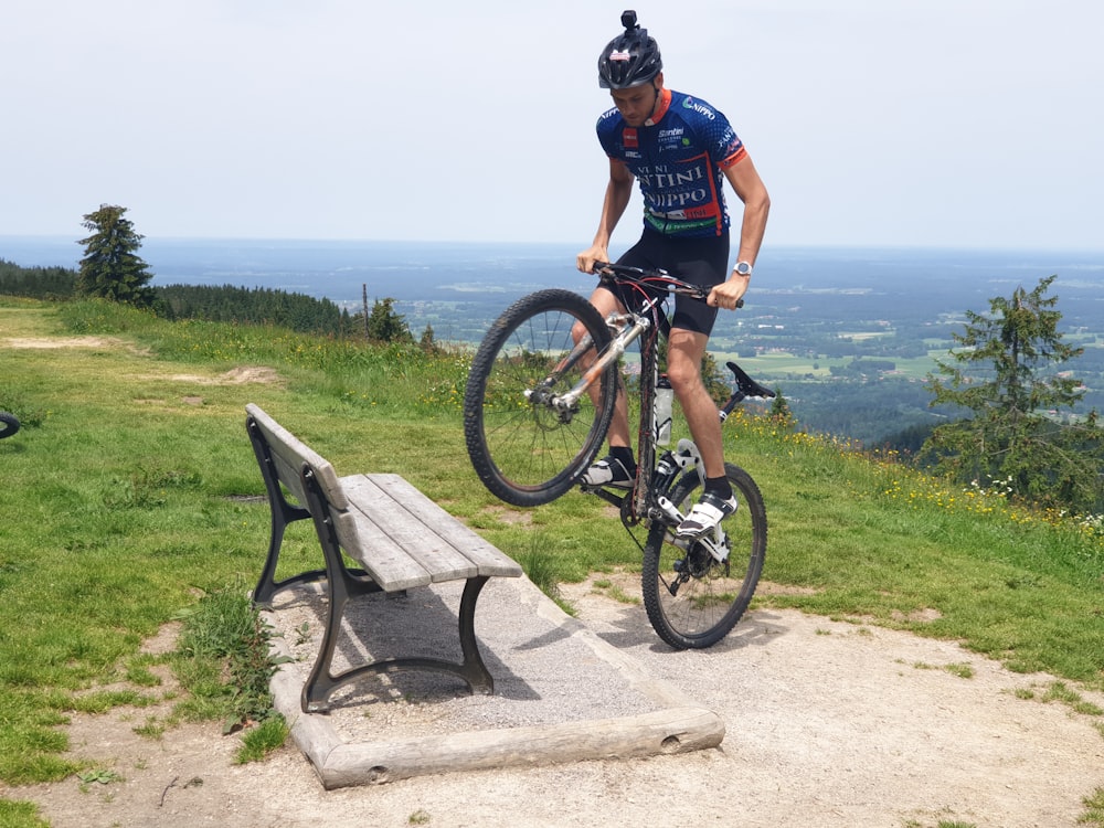 man biking and about to step on gray bench