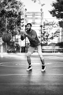 A focused basketball player practicing a drill on an outdoor court.