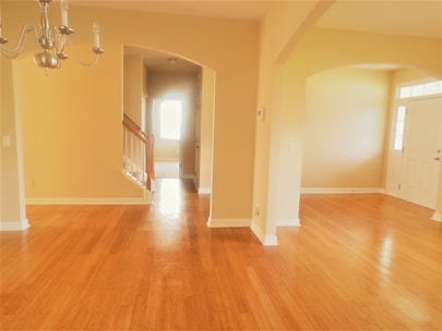 A bright, spacious room showcasing freshly installed hardwood floors with natural light highlighting the wood grain.