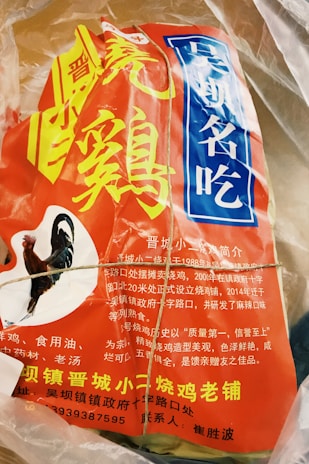 The image contains a package with vibrant red and blue labeling featuring Chinese characters. The package includes an image of a rooster, suggesting it contains poultry or is related to chicken products. The text appears to be informative, likely describing the product or brand.