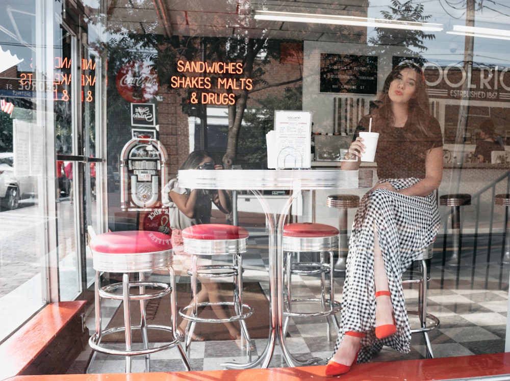 femme assise sur un tabouret de bar à l’intérieur de sandwichs shakes malts et drogues