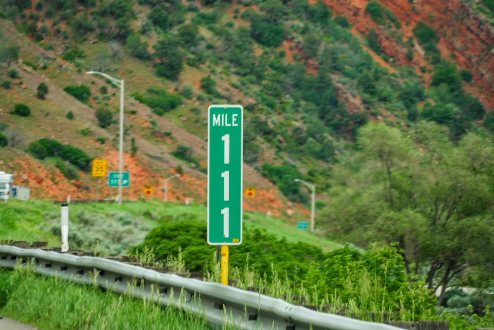 green and white Mile 111 road marker