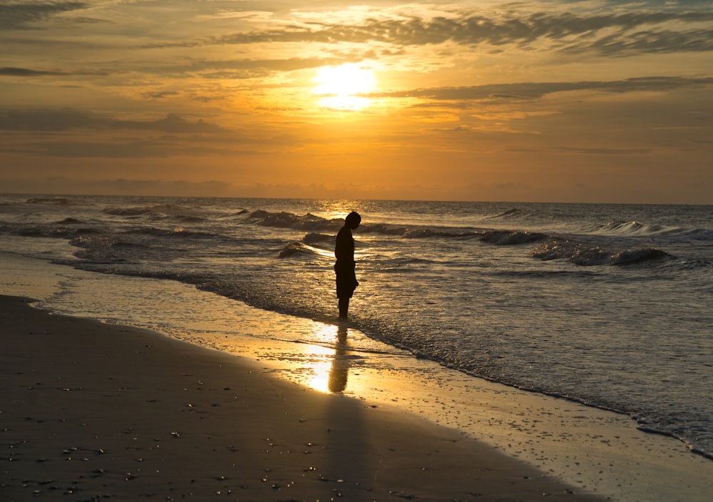 person standing on body of water during golden hour