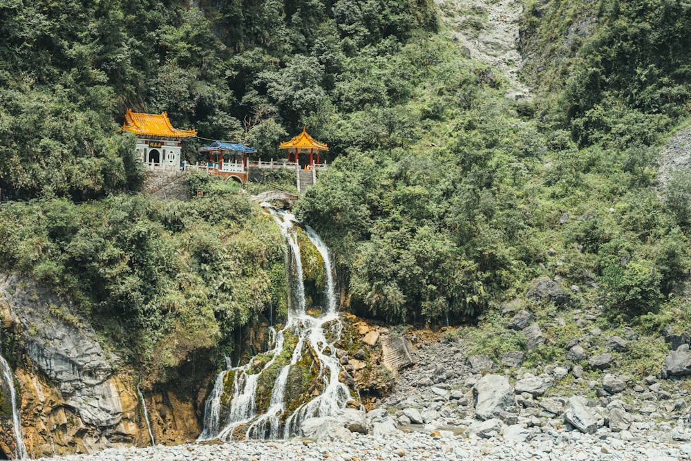 Templo gris, amarillo y azul junto a la ladera de una montaña y una cascada