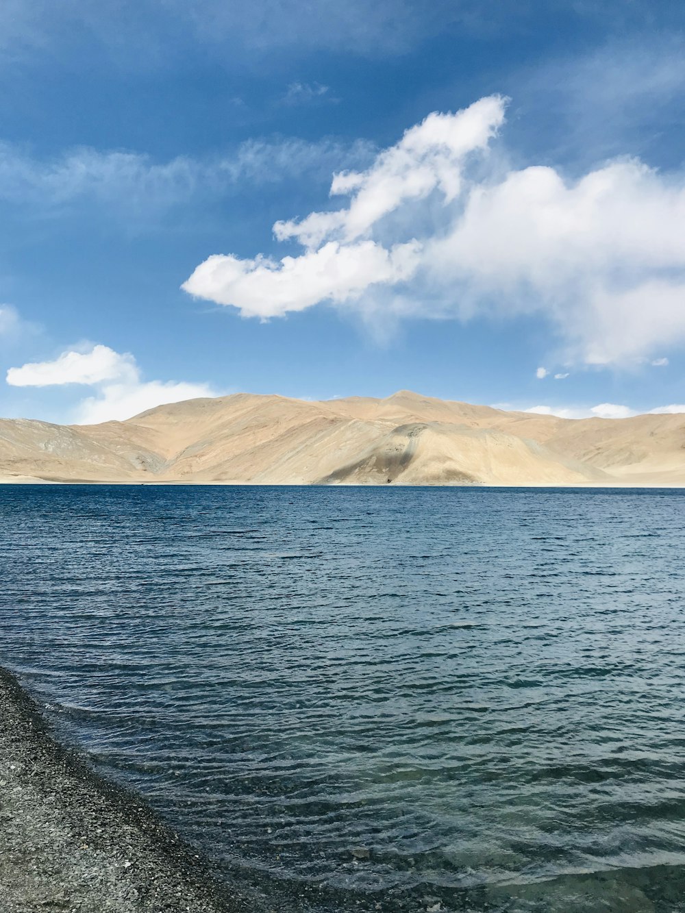 calm body of water near mountain during daytime