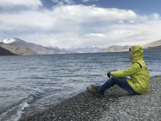 man sitting in front of body of water