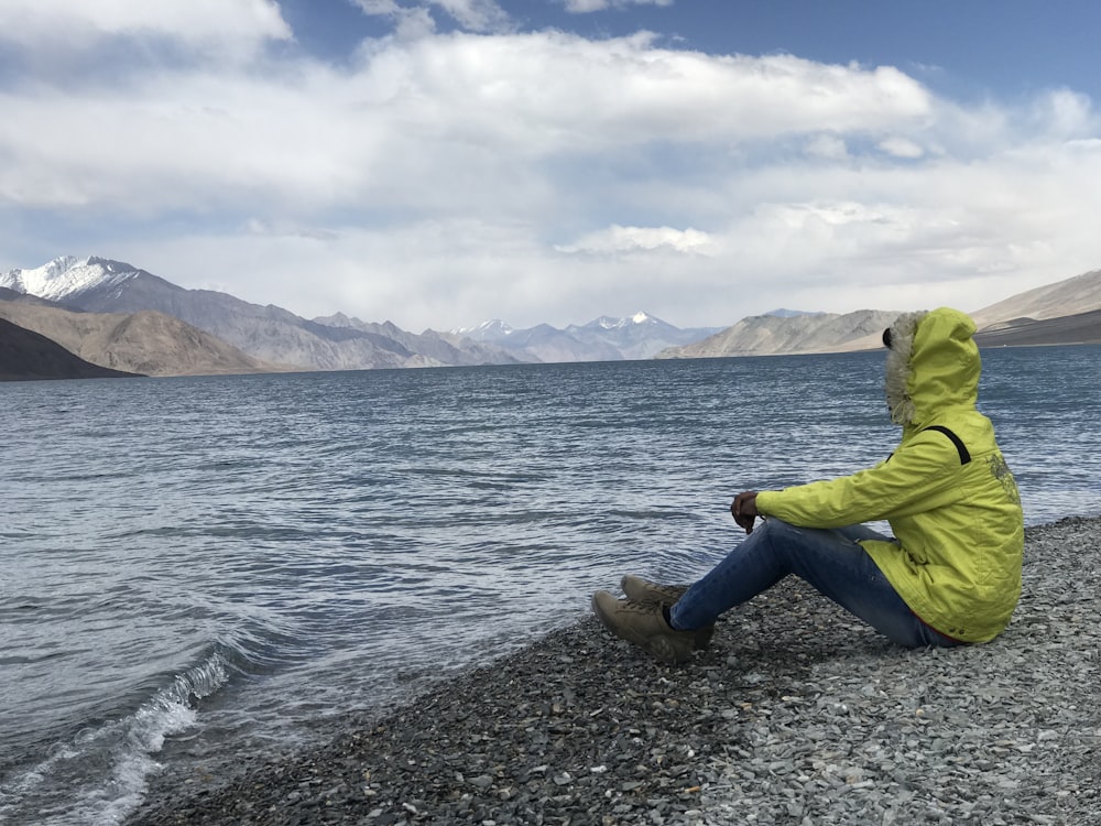 man sitting in front of body of water