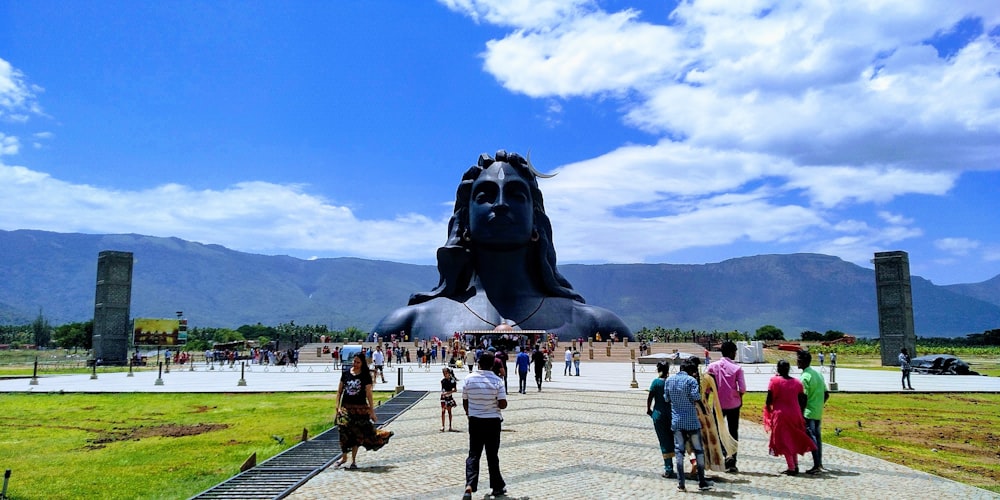 Gente de pie alrededor de la estatua de la cara del hombre en el parque